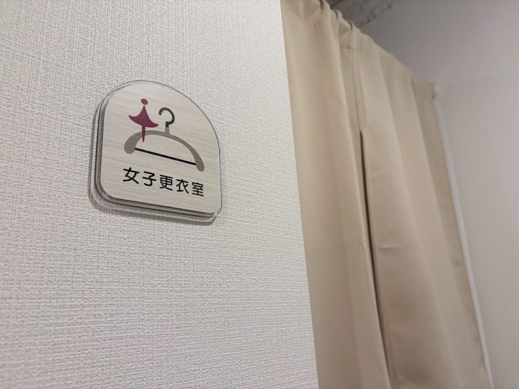 琴似店1階の女子更衣室の入口。木製のプレートとカーテンで仕切られた更衣スペース