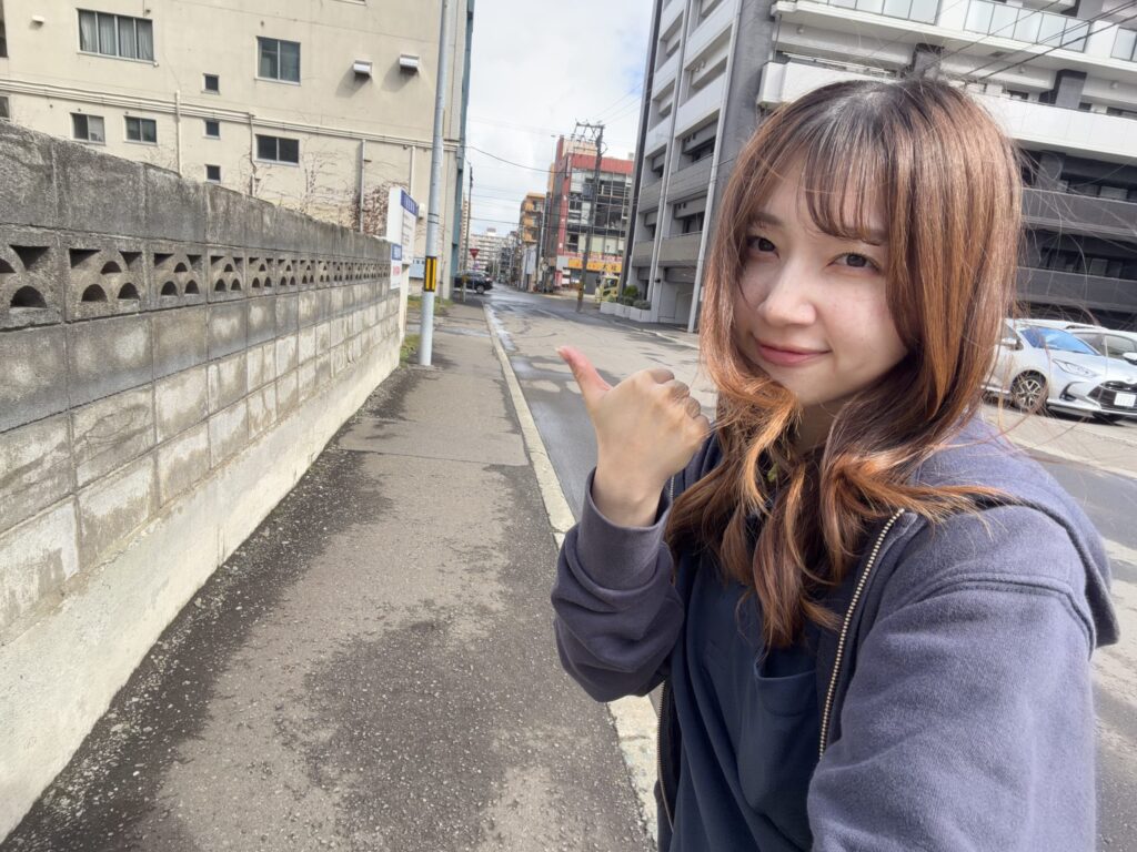 スタッフが歩道に立ち、親指を立てて道の先を示している様子