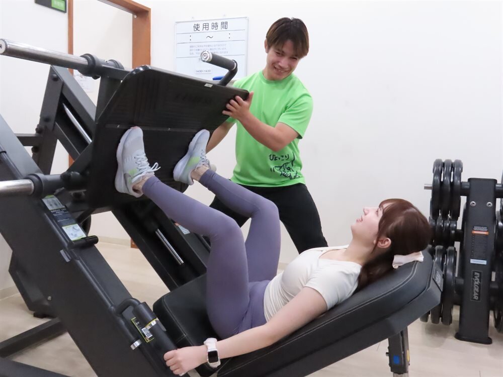 レッグプレスでトレーナーが補助する様子