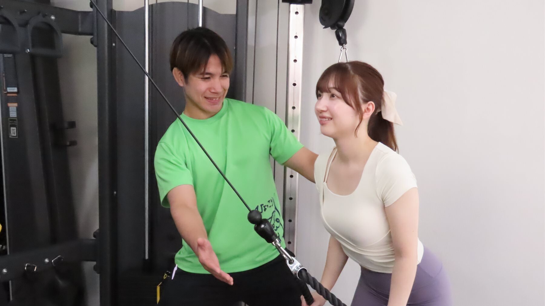 トレーナーとケーブルマシンでトレーニングする女性